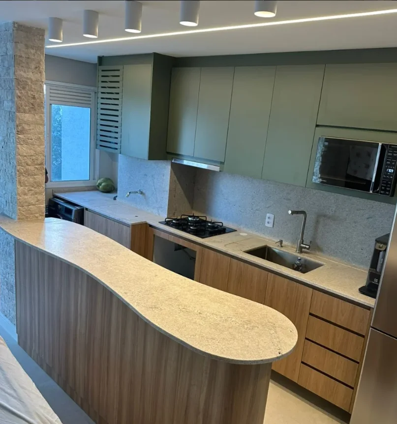 Cozinha com península curva em granito claro, obra da Completa